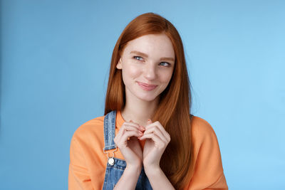 Portrait of a smiling young woman against blue background