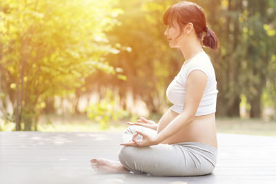 Side view of young woman sitting outdoors