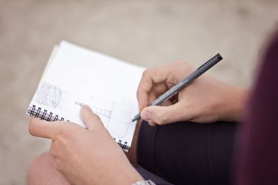 Cropped image of man sketching on book