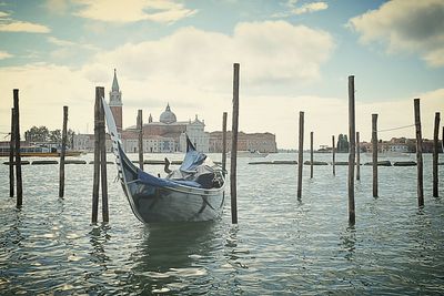 Boats on wooden posts in sea against sky