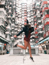 Full length of man jumping against buildings in city