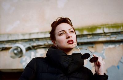 Young woman standing against building