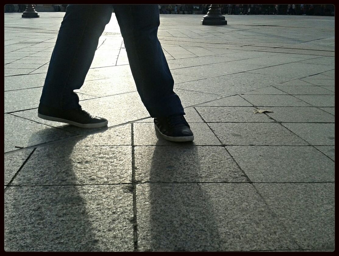 low section, shadow, person, sunlight, lifestyles, street, walking, men, sidewalk, standing, high angle view, paving stone, tiled floor, unrecognizable person, leisure activity, footpath, cobblestone