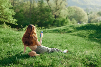 Rear view of woman sitting on grassy field