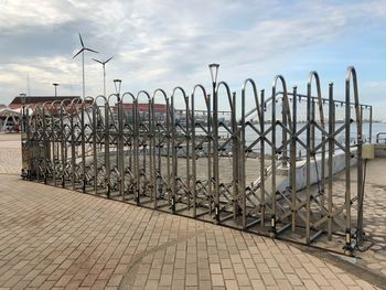 Bicycles on railing by sea against sky