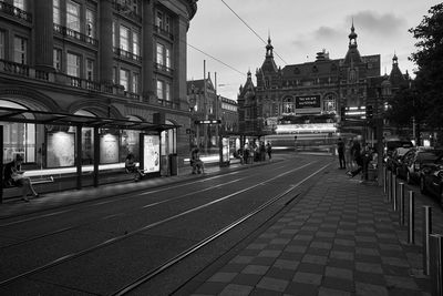 Railroad tracks on road in city at dusk