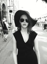 Portrait of beautiful woman wearing sunglasses while standing on street