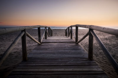 Pier over sea against sky during sunset