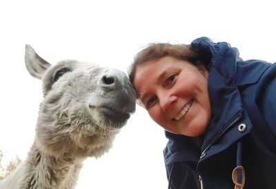 Portrait of smiling young woman against sky and donkey