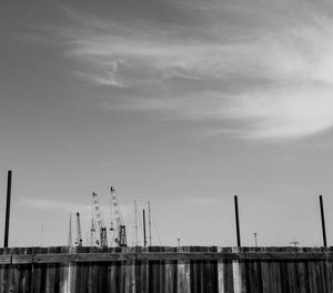 Cranes at harbor against sky