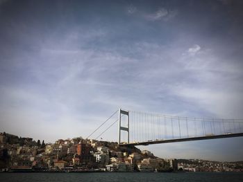 Bridge over sea by city against sky
