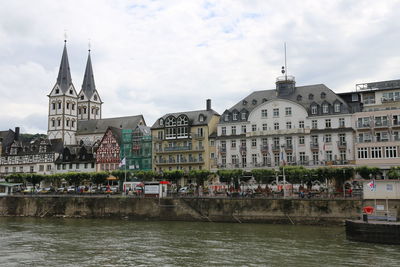 Buildings at waterfront against cloudy sky