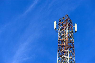 Low angle view of communications tower against blue sky