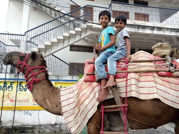 Full length portrait of boys sitting on camel