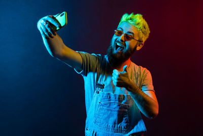 Young man using smart phone against black background