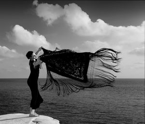 Woman standing by sea against sky