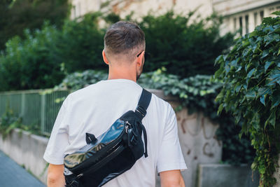 Rear view of man wearing backpack standing outdoors