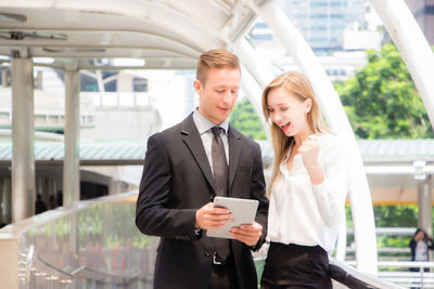 Young couple holding smart phone while looking at camera