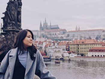 Young woman standing by river in city