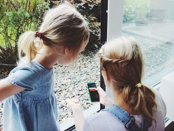 Mother with daughter using phone by window at home