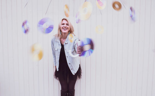 Portrait of a smiling young woman standing against wall