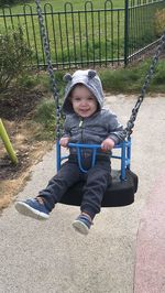 Full length portrait of happy baby boy enjoying on swing at park