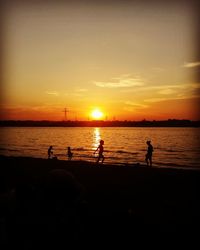 Silhouette people on beach against sky during sunset