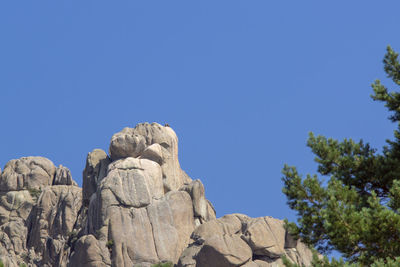 Low angle view of rocks against clear blue sky