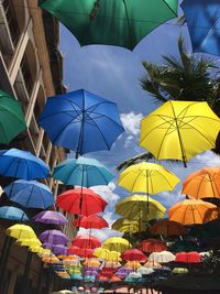 Low angle view of multi colored umbrellas hanging against sky