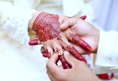 Cropped image of groom inserting wedding ring in bride finger during ceremony