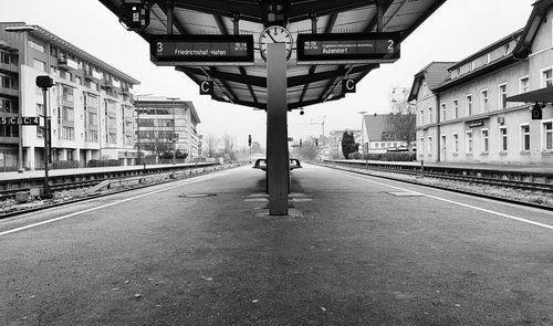Railroad station platform in city against sky