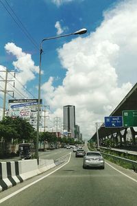 Cars on street in city against sky