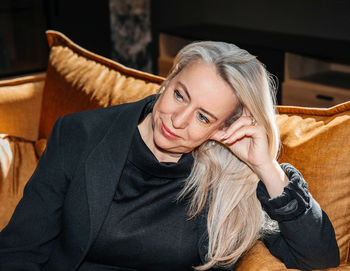 Mature woman relaxing on a mustard yellow velvet couch