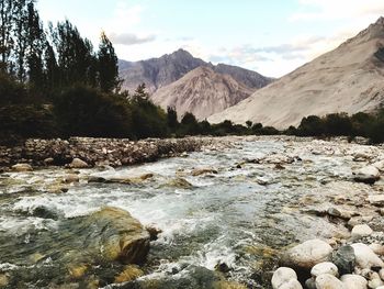 Scenic view of river by mountains against sky
