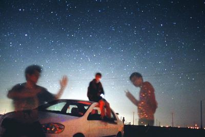 Friends standing against sky at night