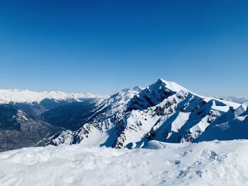 Scenic view of snowcapped mountains against clear blue sky