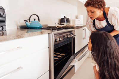 Side view of young woman standing in kitchen