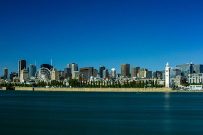 Scenic view of sea and buildings against clear blue sky