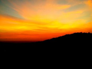 Scenic view of silhouette mountains against orange sky