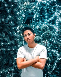 Portrait of smiling man standing against illuminated plants