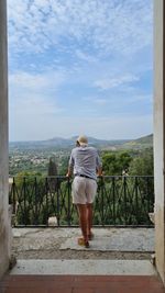 Man looking out from a balcony to italian landscape. shot from back