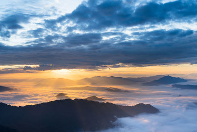 Scenic view of dramatic sky over silhouette mountains during sunset