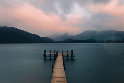 Pier on lake against sky during sunset