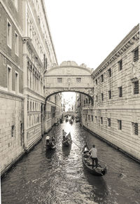 People on boat in canal against clear sky