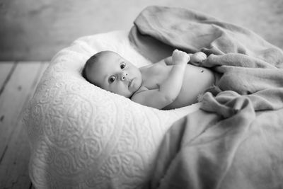 Cute baby girl lying on bed at home
