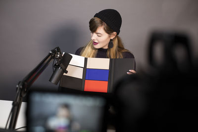 Businesswoman looking at product while recording through television camera