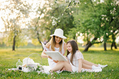A mother and daughter in the spring garden on a plaid leaf through and look through a book