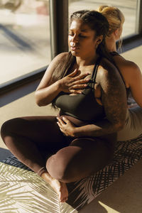 Woman with hand on chest exercising with female friend at retreat center