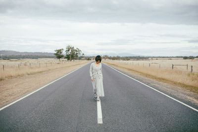 Full length of woman walking on road against sky