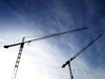 Low angle view of cranes and construction site against sky